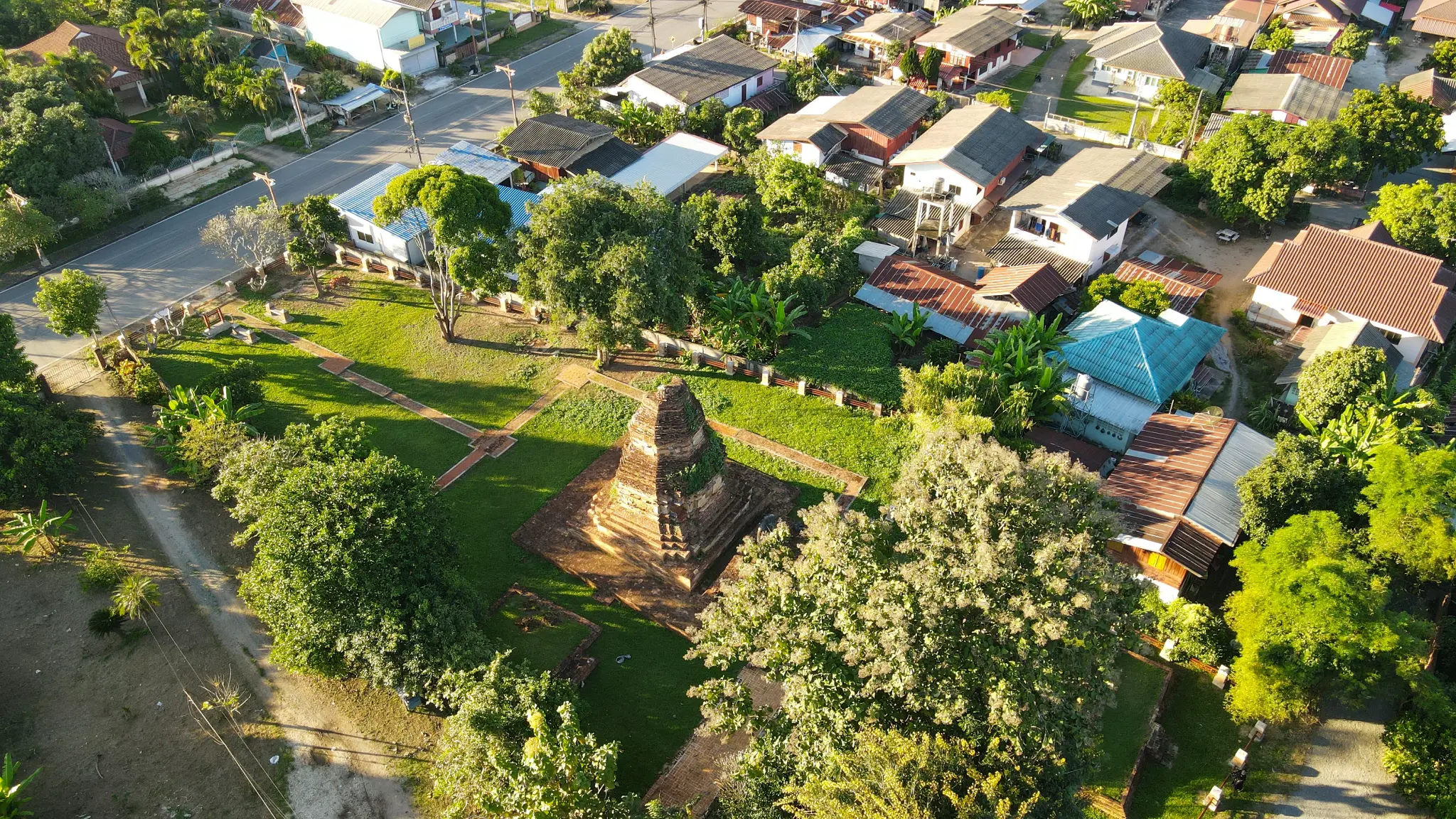 Aerial view of an ancient stupa among green trees and houses in Chiang Saen