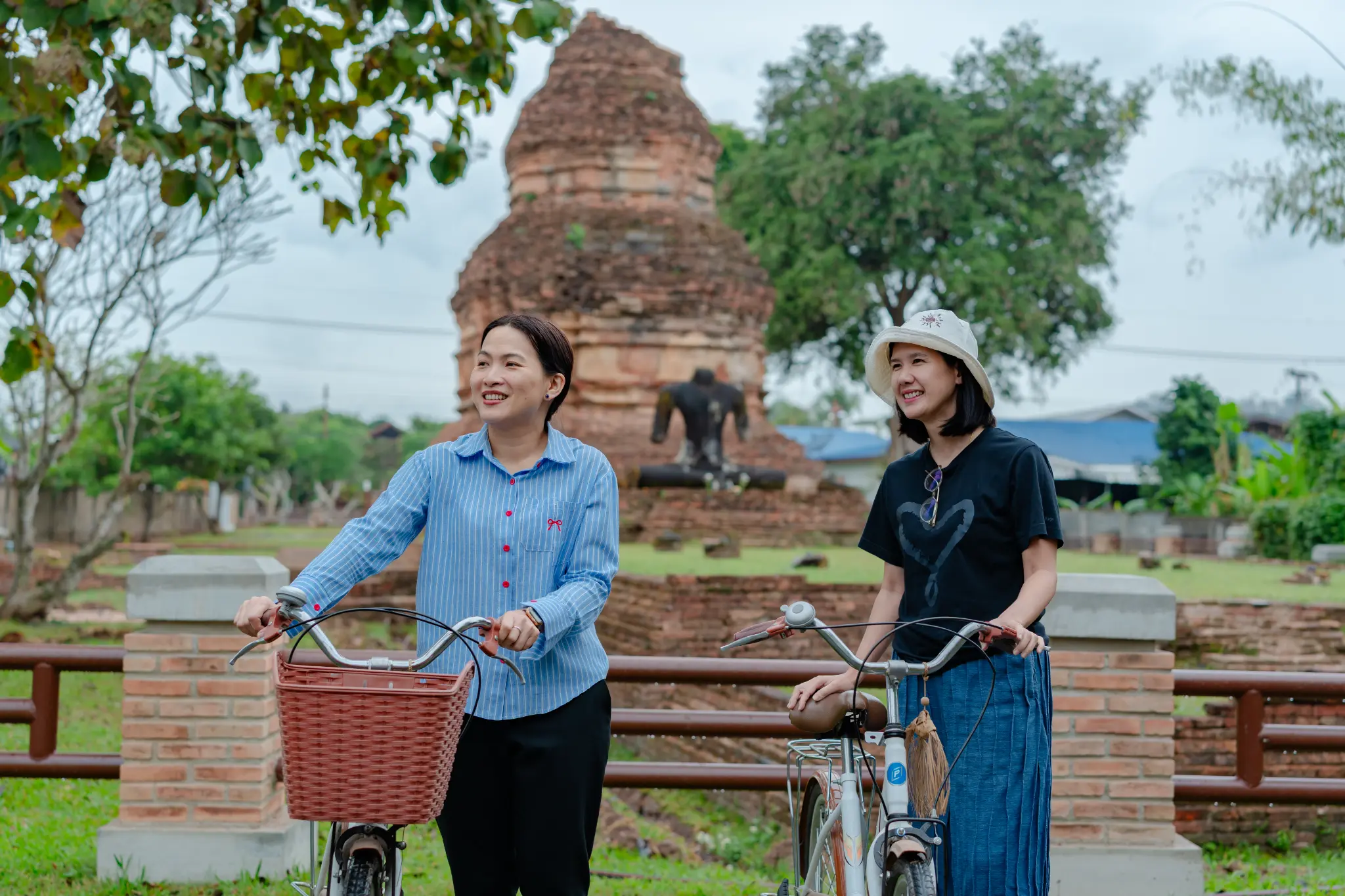 Two women standing with bicycles in front of ancient brick ruins