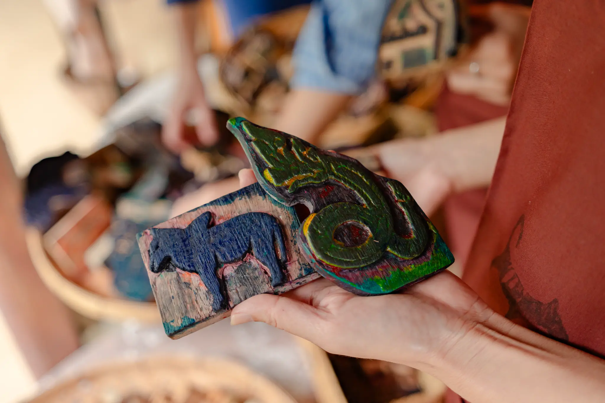 Hands holding two intricately carved wooden blocks