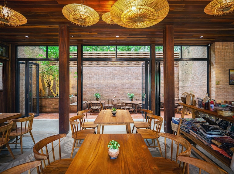 Athita's timber dining room opening toward the brick courtyard