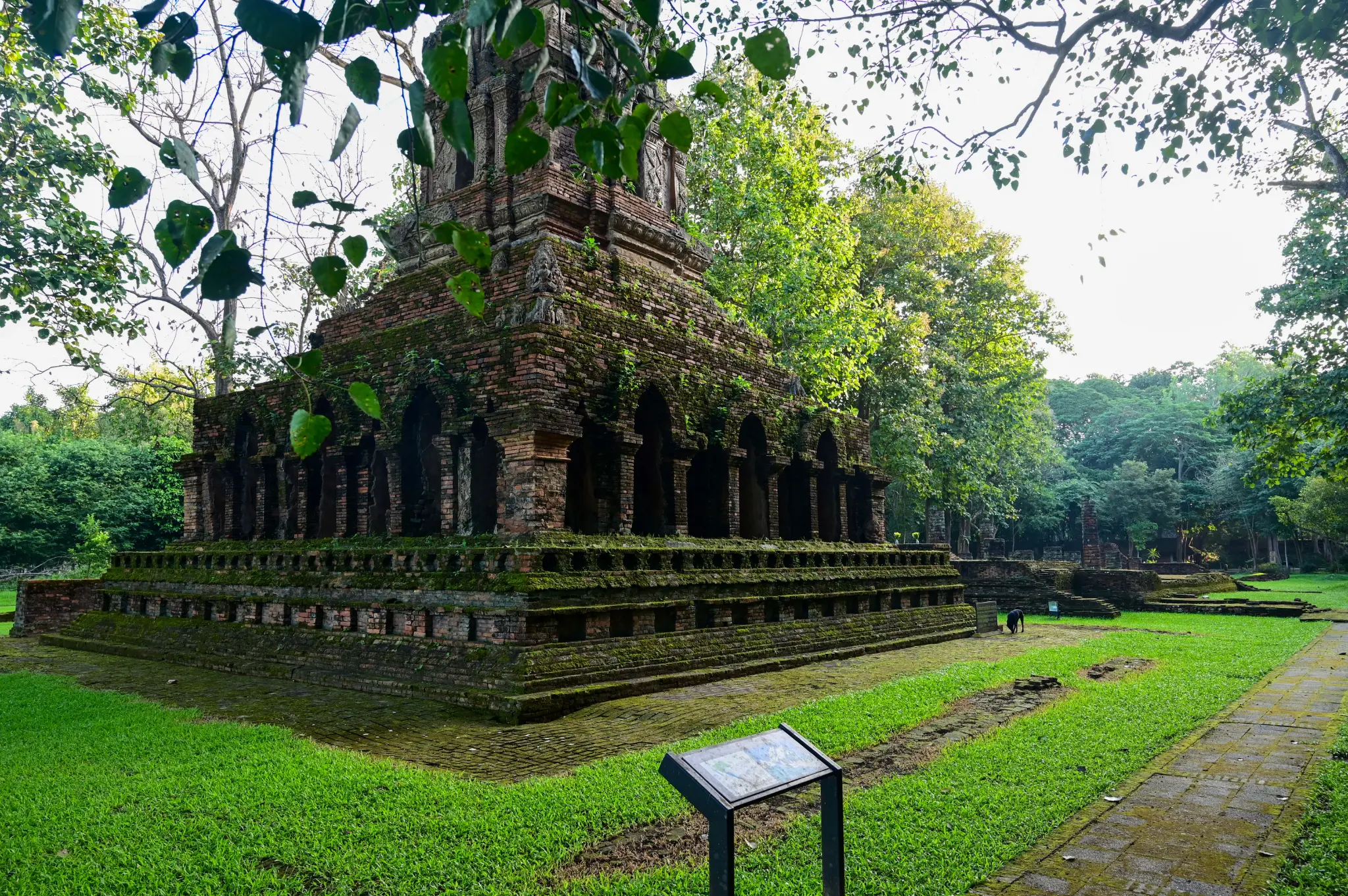 Moss-covered ancient ruins beside a stone path in a lush green setting