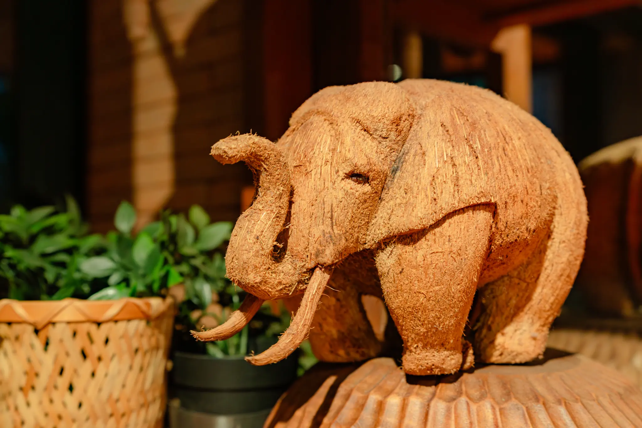 An elephant sculpture made from natural fibrous material on a decorative base